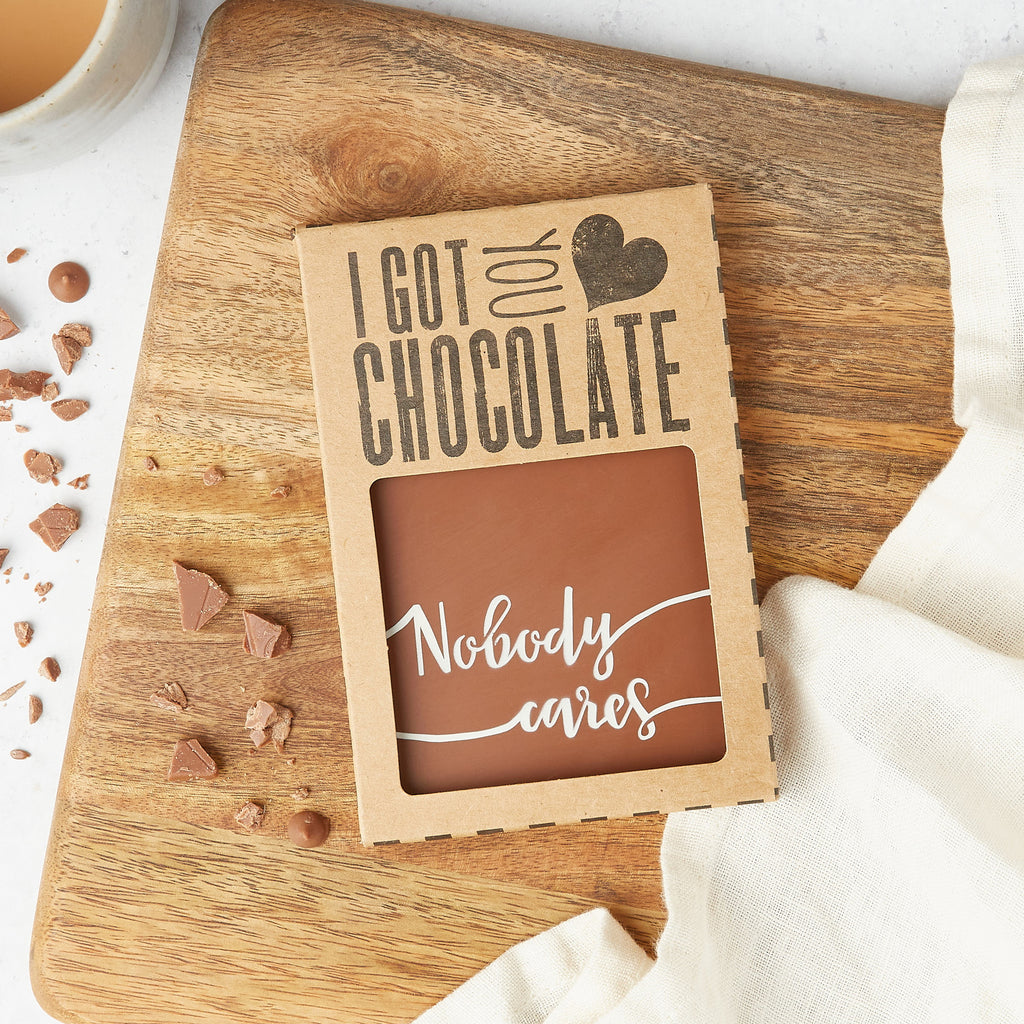 Flat lay image of gift packaged chocolate bar with 'Nobody cares' written on in coloured cocoa butter